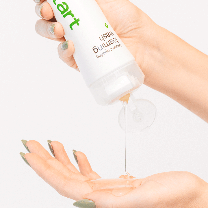 Eine Hand hält eine Flasche und drückt eine klare Flüssigkeit in die andere Hand.