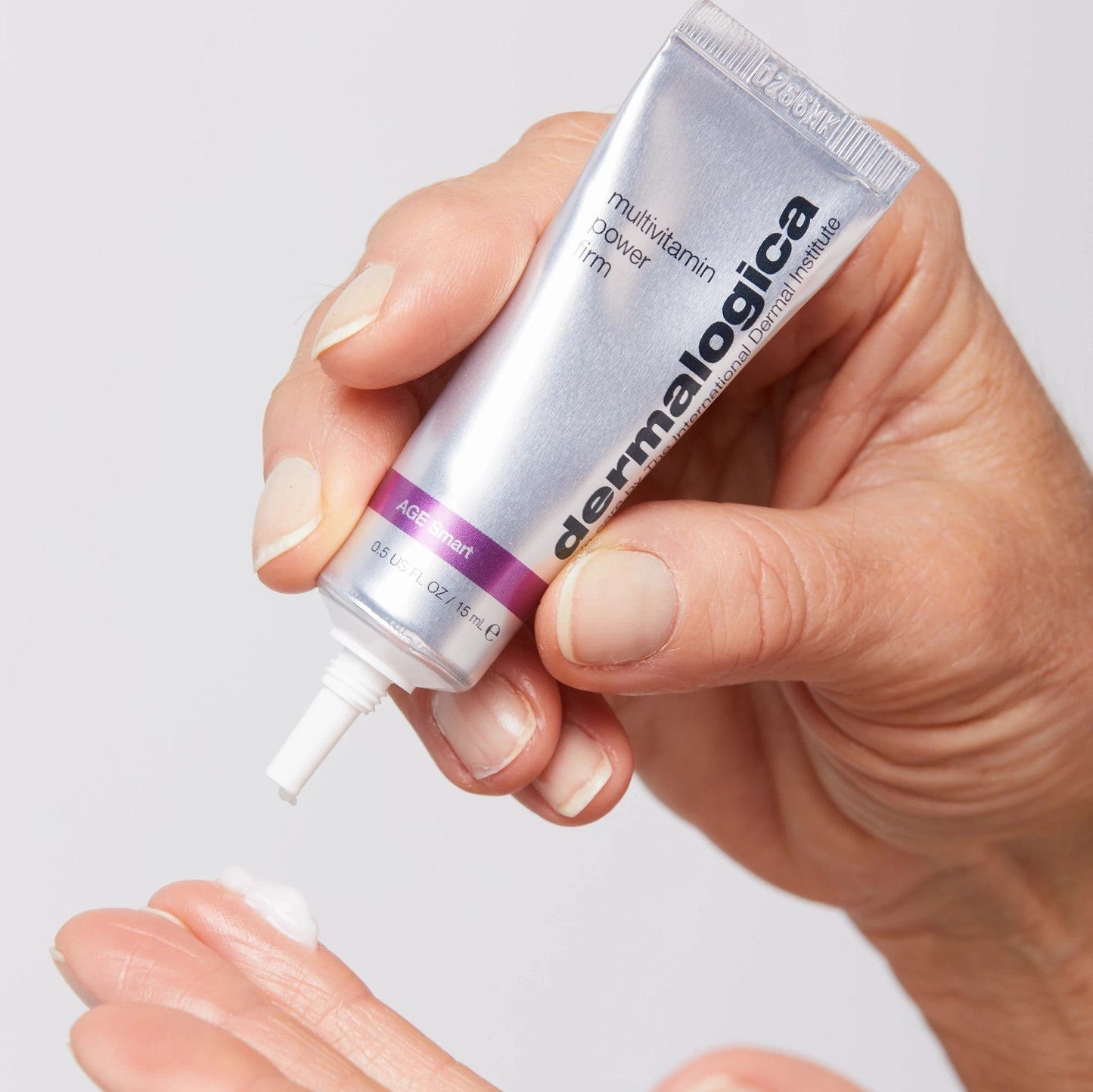 Hand drückt eine kleine Menge Creme aus einer Tube der Marke Multivitamin Power Firm heraus.