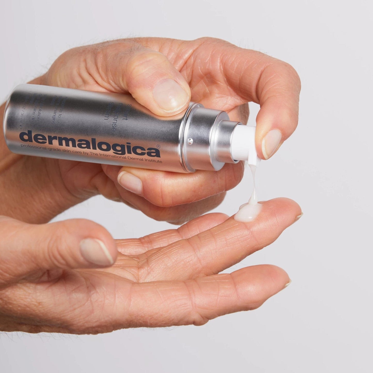 Eine Hand drückt eine Lotion oder Creme der Marke aus einem Spender auf den Handrücken einer anderen Hand.