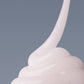 Ein Wirbel aus dicker, weißer Creme, der an das Pro-Collagen Banking Serum erinnert, hebt sich von einem schlichten grauen Hintergrund ab.