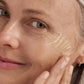 Nahaufnahme einer Frau, die das Dynamic Skin Retinol Serum mit den Fingern auf ihre Wange aufträgt, um sichtbare Falten und die natürliche Hautstruktur zu betonen.
