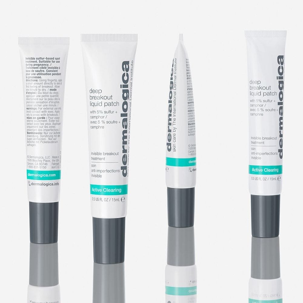 Vier Tuben Deep Breakout Liquid Patch stehen aufrecht auf einer weißen, reflektierenden Oberfläche - diese vegane Hautpflege wirkt wie ein unsichtbares Pickelpflaster und eine innovative Schwefelbehandlung für Pickel, wobei die Produktdetails und das Branding deutlich sichtbar sind.