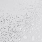 Wassertropfen unterschiedlicher Größe, die über eine glatte, hellgraue Oberfläche verstreut sind, erinnern an die erfrischende Note von Antioxidant HydraMist.