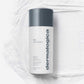 Ein Behälter mit Daily Microfoliant | Gesichtspeeling mit grauem Deckel steht auf einer strukturierten weißen Oberfläche und enthält einen einzigartigen Skin Brightening Complex zur Revitalisierung Ihres Teints.
