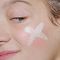 Eine Nahaufnahme eines Gesichts mit einem weißen X auf der Wange, möglicherweise mit Creme oder Routine Frühlingshaut gezeichnet - ideal für empfindliche Haut.