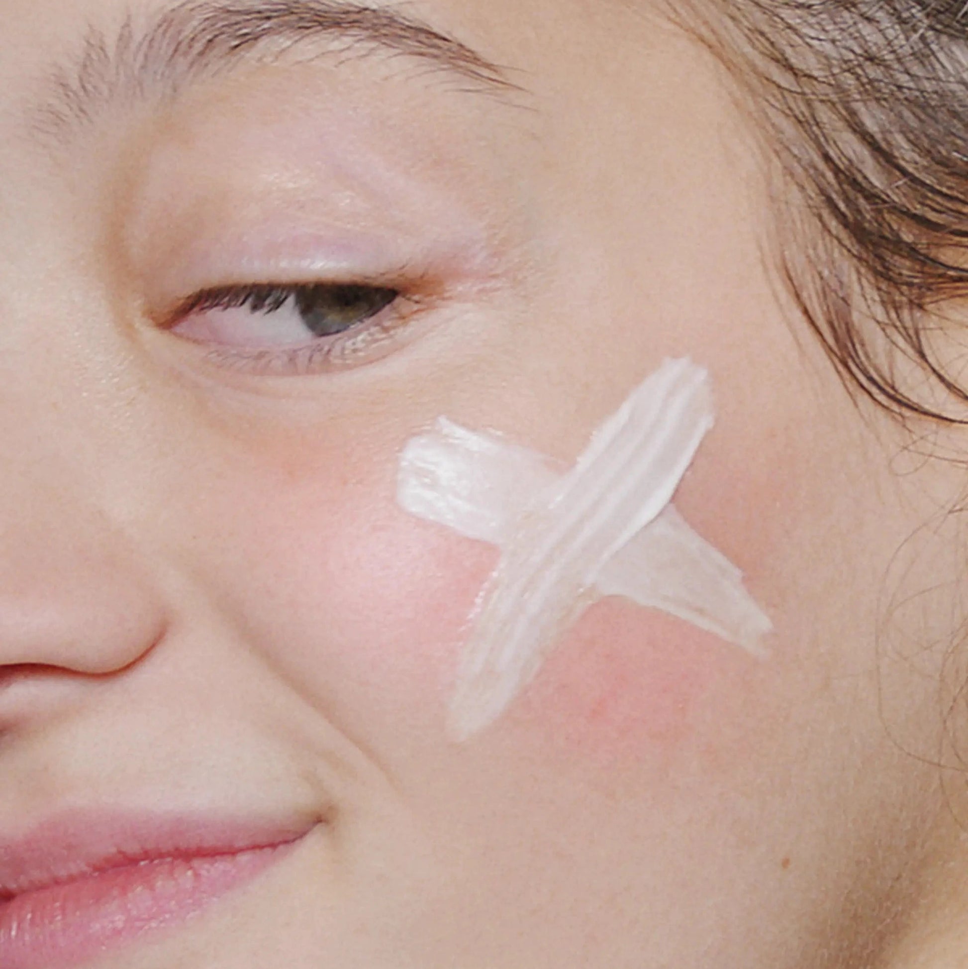 Eine Nahaufnahme eines Gesichts mit einem weißen X auf der Wange, möglicherweise mit Creme oder Routine Frühlingshaut gezeichnet - ideal für empfindliche Haut.