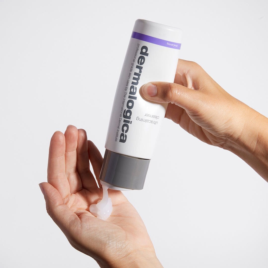 Eine Person verteilt ein klares Gel aus einer Routine-Frühlingshaut-Flasche auf ihrer Handfläche, ideal für empfindliche Haut, vor einem schlichten weißen Hintergrund.