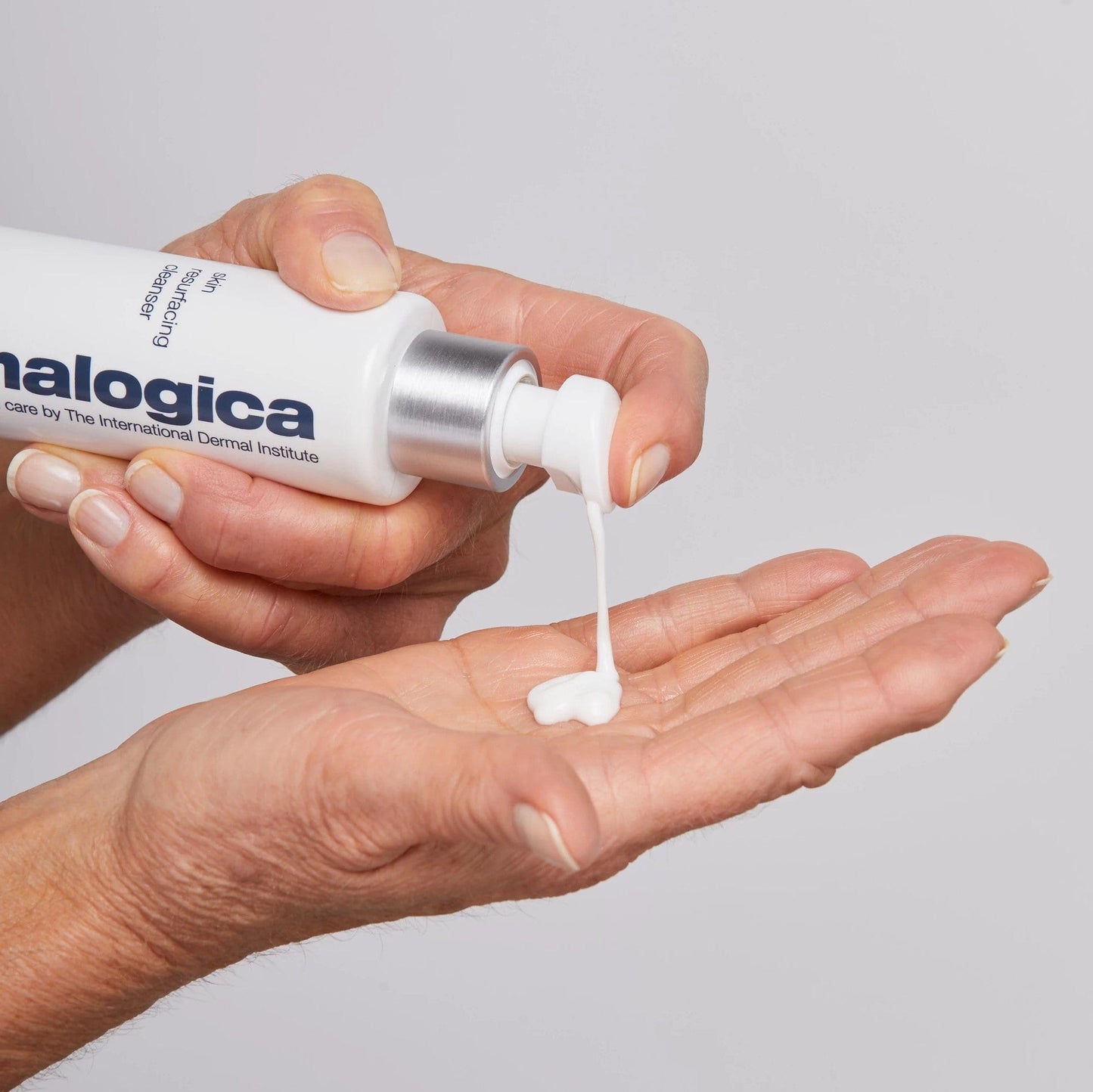 Eine Hand drückt eine kleine Menge einer weißen Creme aus einer in die andere Handfläche.