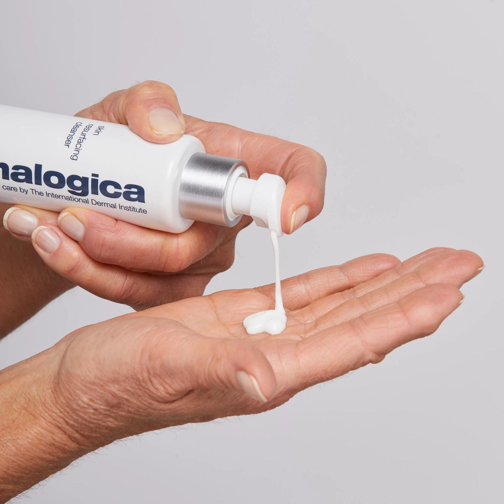 Eine Hand drückt eine kleine Menge einer weißen Creme aus einer in die andere Handfläche.
